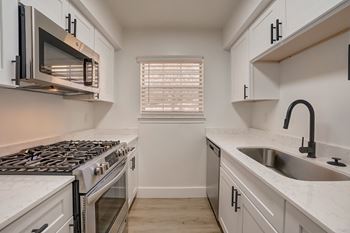 a kitchen with white cabinets and a sink and a stove